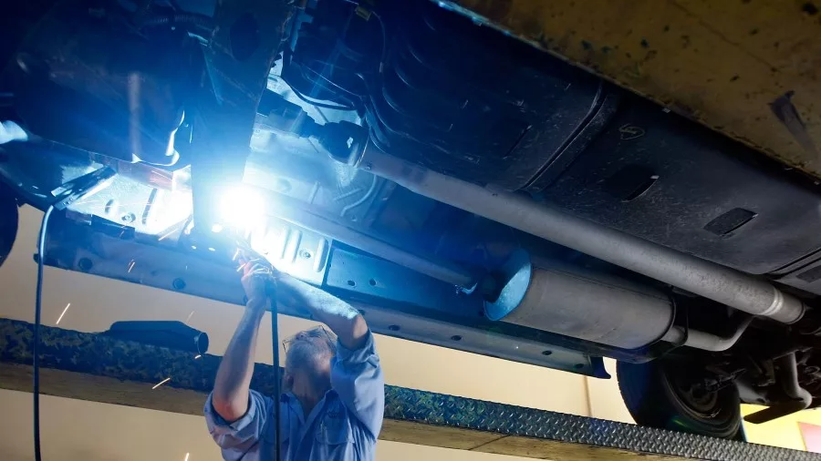 Kevin Doyle from Mad Hatter Muffler shop works on replacing a catalytic converter on a truck (Getty...