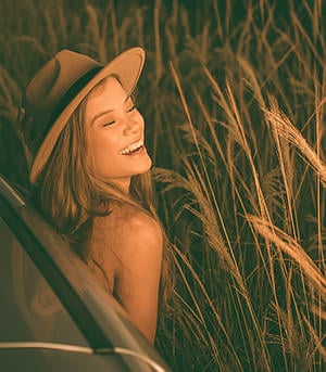 Happy woman in field at sunset